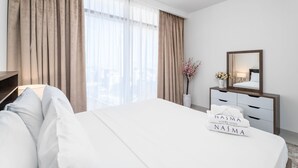 Hotellihuone, jossa on suuri sänky, lipasto, peili ja ikkuna, jossa on verhot.