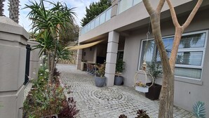 A courtyard with potted plants, a hanging light fixture, and a stone-tiled floor. - Palmzicht (Cape Town)