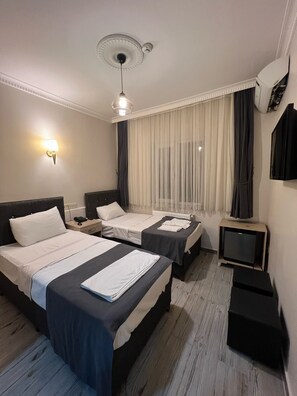 A hotel room with two beds, a ceiling fan, a TV, and a wall-mounted air conditioner. - Oren Hotel (Istanbul)