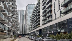 A modern urban street lined with high-rise residential buildings, featuring balconies and large windows. - RentPlanet - Studio Kasprzaka (Warsaw)