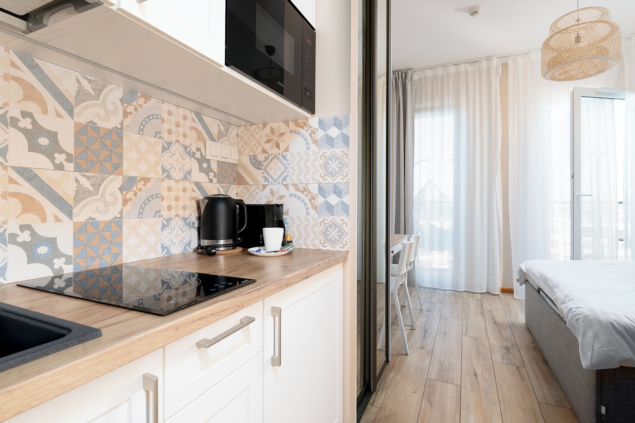 A modern kitchen with a black induction cooktop, a coffee maker, and a white cup on the counter.