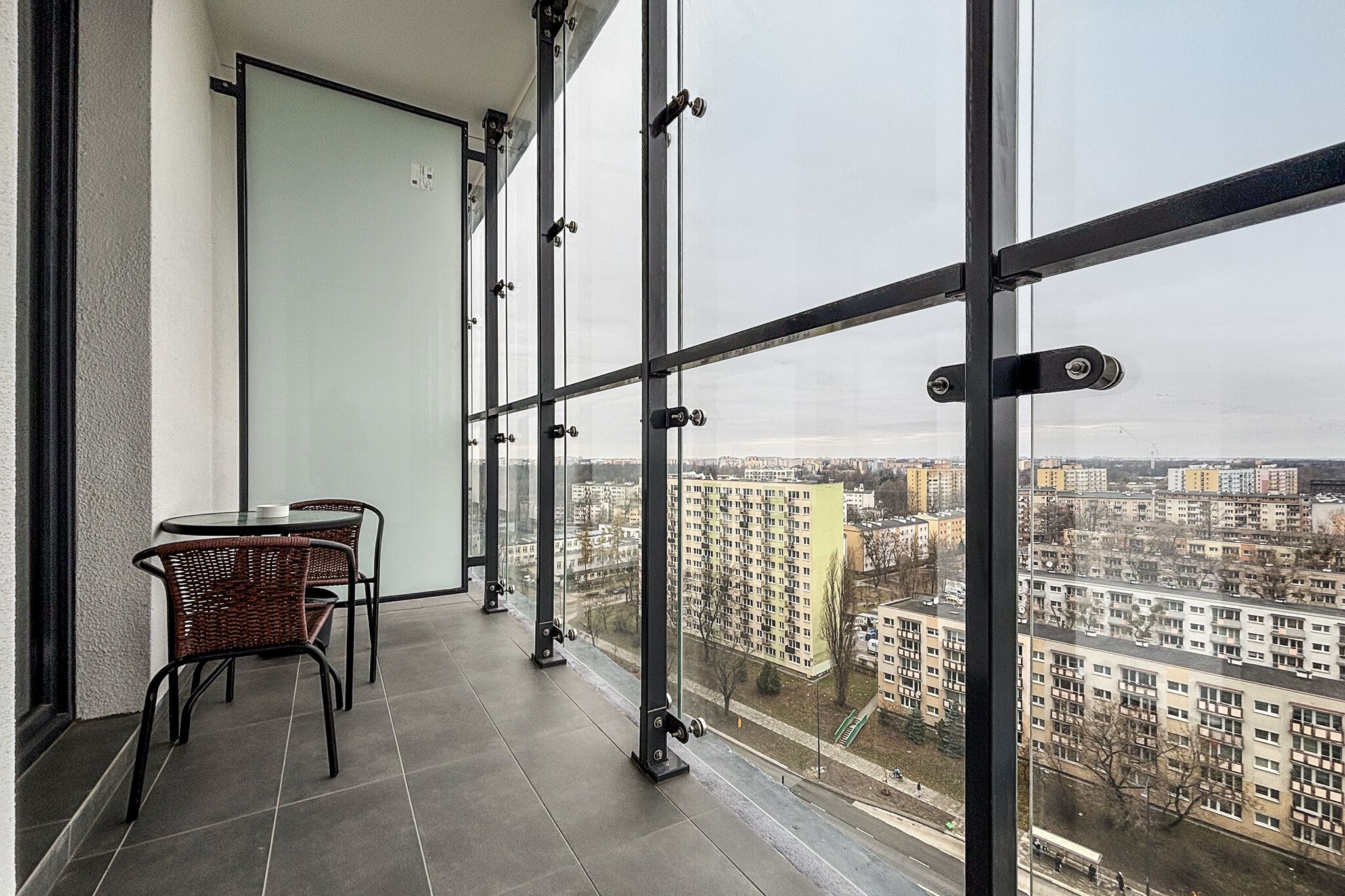 A balcony with a view of a cityscape, featuring a table and chairs.