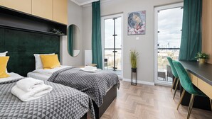 A modern hotel room with two beds, a dining area, and a large window with a city view. - RentPlanet - Studio Kasprzaka (Warsaw)