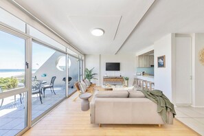A modern living room with a sofa, a dining area, and a TV.