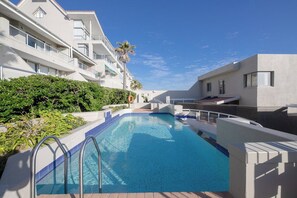 A swimming pool surrounded by modern buildings, with a clear sky above.