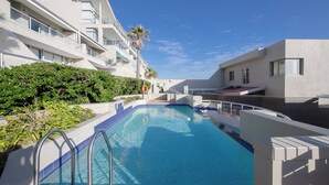 A modern hotel with a swimming pool, white balconies, and palm trees. - Dolphin Beach CG12, Blouberg by HMH (Cape Town)