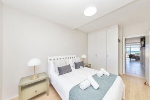 Quarto com cama, mesa de cabeceira e vista para o exterior.