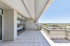 Un balcon offrant une vue dégagée sur le paysage, une porte-fenêtre coulissante donnant sur une pièce et une rambarde.