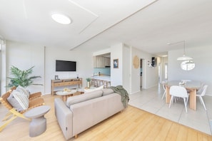 Uma sala de estar moderna com sofá, mesa de centro e área de jantar com cadeiras.