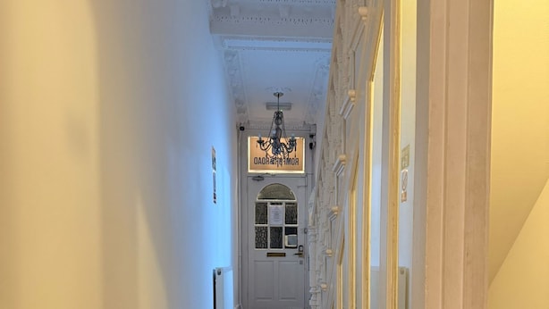 A hallway with wooden flooring, white walls, and a door at the end.