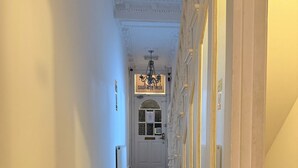 A hallway with wooden flooring, white walls, and a door at the end.