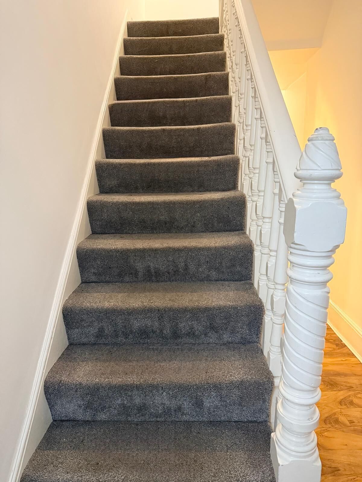 A carpeted staircase with a white balustrade.