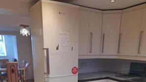 A modern kitchen with white cabinets, a built-in oven, and a trash bin.