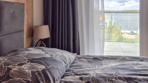 Makuuhuone, jossa on sänky, lamppu ja näkymä järvelle.
