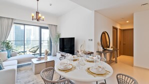 A modern living room with a dining area, a flat-screen TV, and a view of the cityscape.