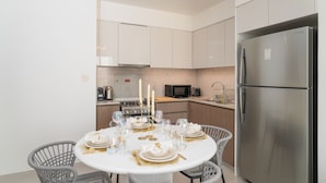 A modern kitchen with stainless steel appliances, a dining area with a round table set for six, and a built-in oven.