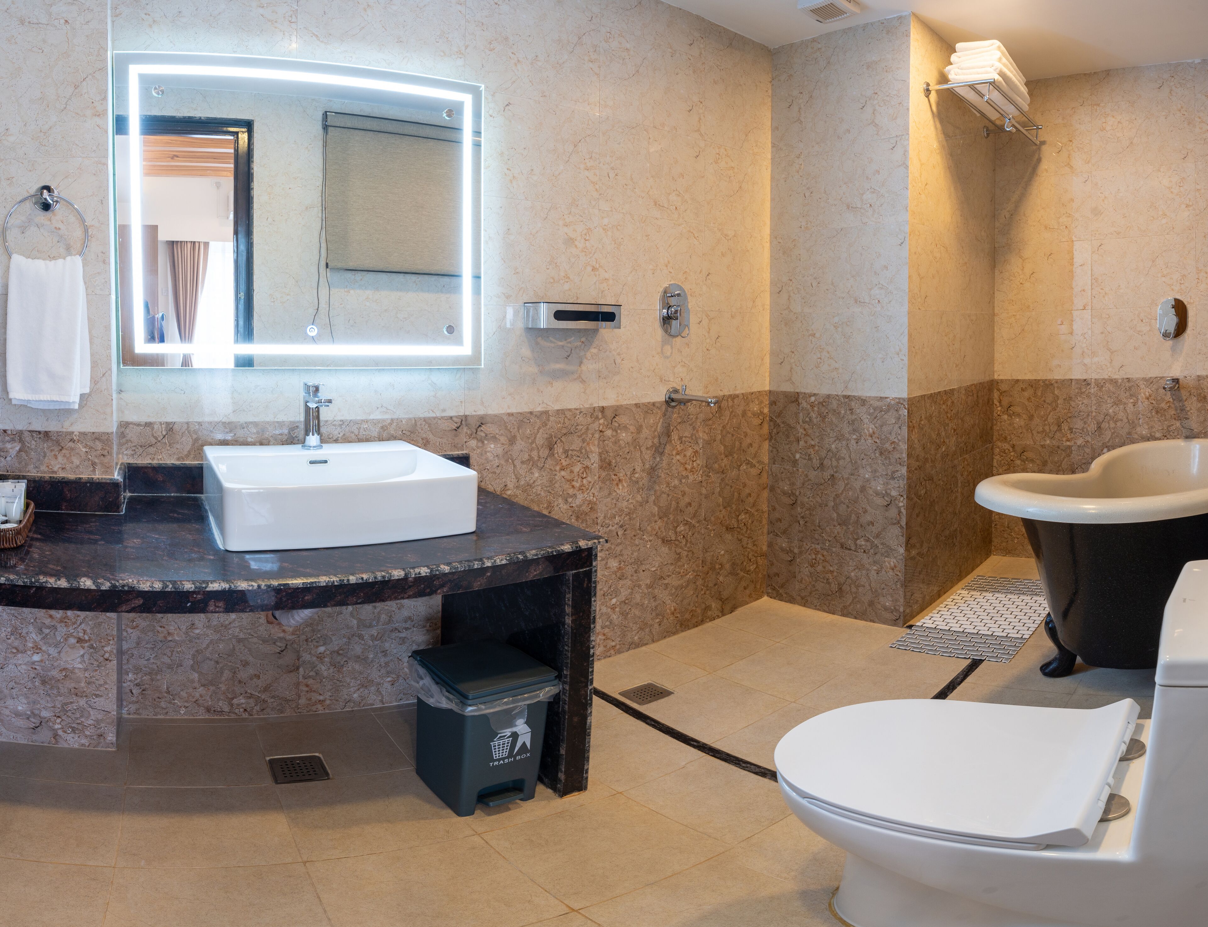 Un baño moderno con lavabo de mármol, un espejo grande, inodoro y zona de ducha.