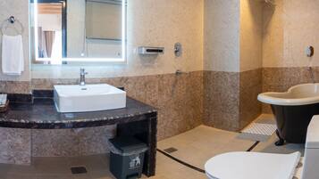 Un baño moderno con lavabo de mármol, un espejo grande, inodoro y zona de ducha.