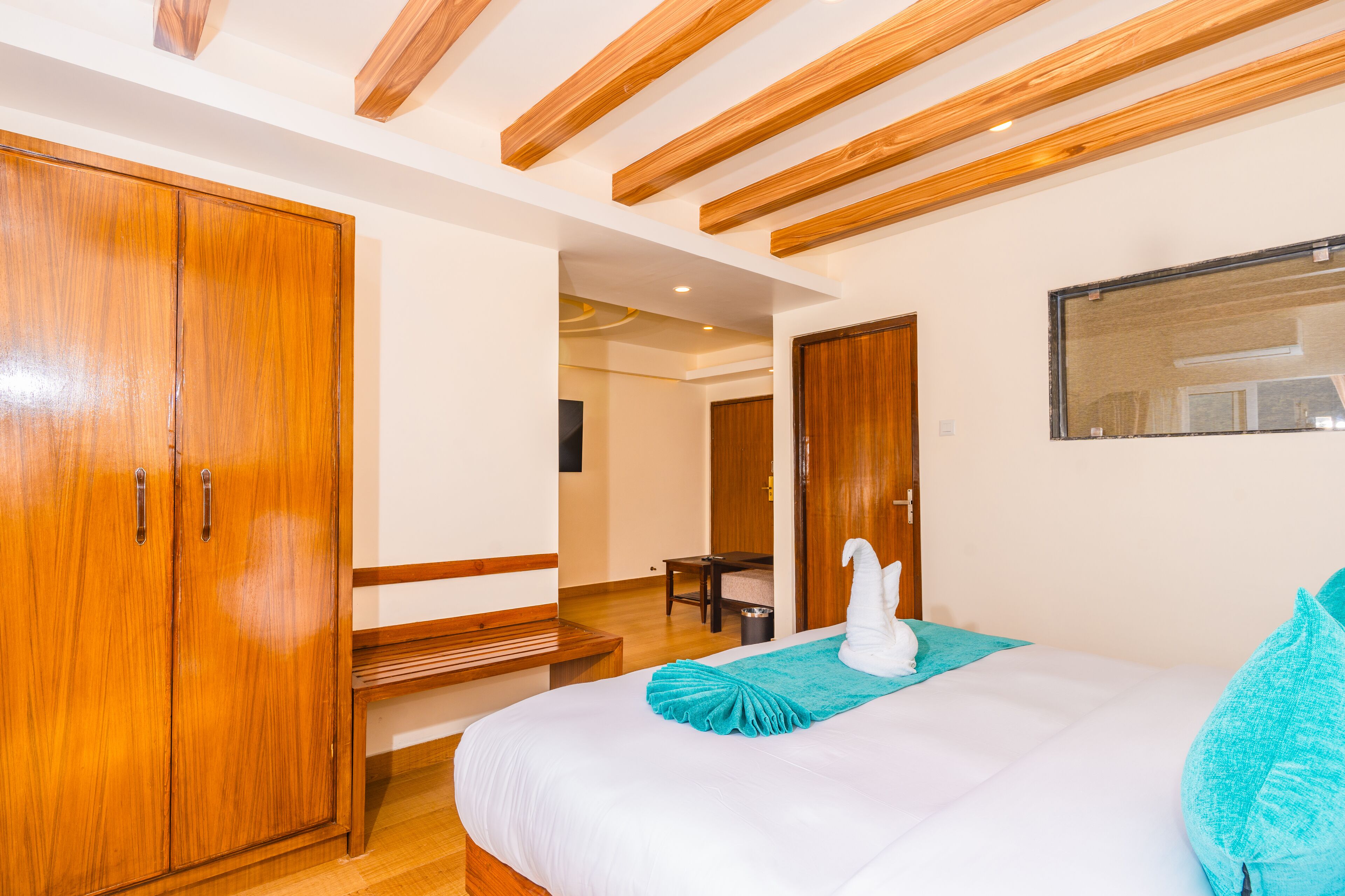 Un dormitorio con un armario de madera, una cama con adorno de cisne blanco y un cojín color aguamarina.