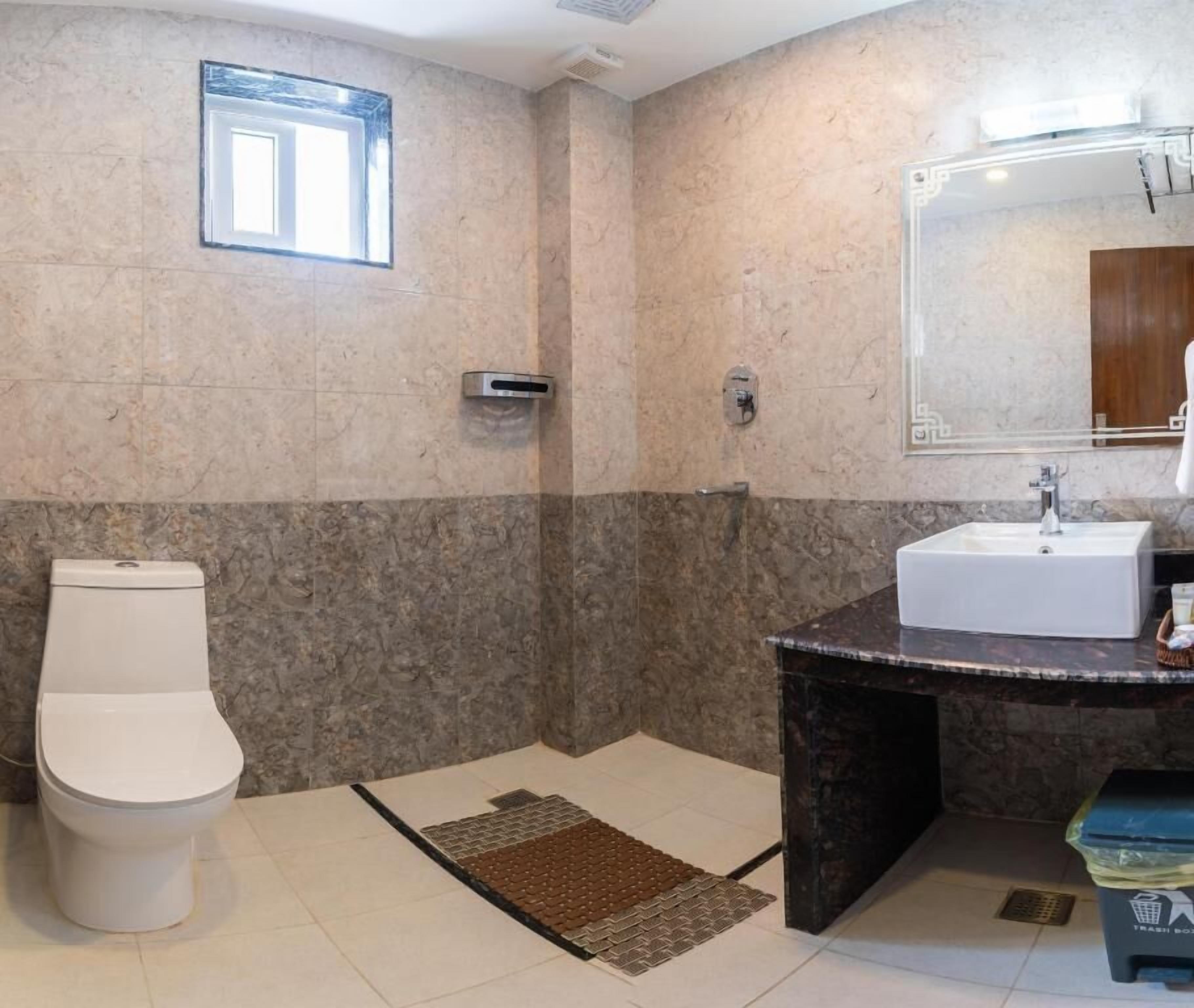Et badeværelse med toilet, håndvask og bruseområde.