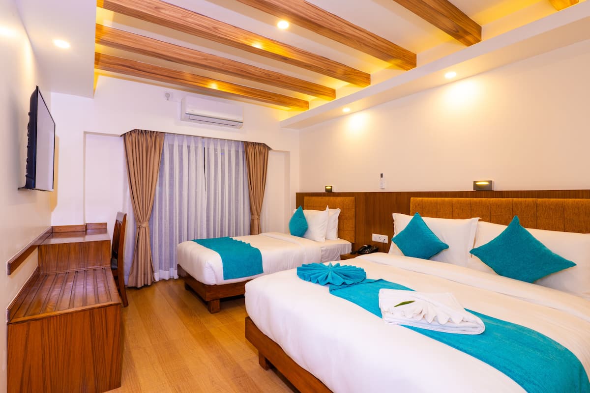 A hotel room with two beds, a wooden desk, and a TV.