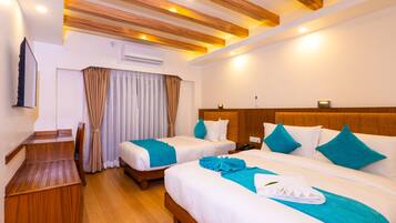 A hotel room with two beds, a wooden desk, and a TV.