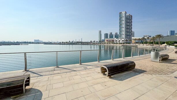 Eine Uferpromenade mit Bänken und freiem Blick auf die Stadtlandschaft.