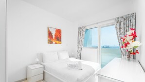 Ein modernes Schlafzimmer mit Bett, Nachttischen, Vorhängen an einem Fenster und Blick auf die Stadt.