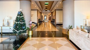 Eine Hotelhalle mit Weihnachtsbaum, einer Rezeption und einem Check-in-Schalter.