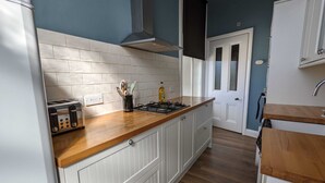 Een keuken met witte kastjes, een houten aanrecht, een gasfornuis en een broodrooster.