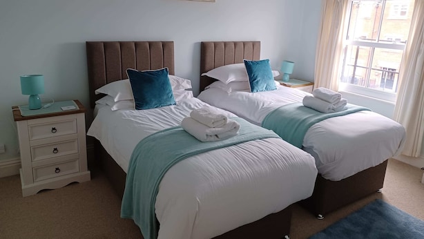 A double bed with a headboard, a bedside table with a lamp, and a window with curtains.