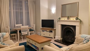 A living room with a fireplace, a television, and a dining area with chairs and a table.
