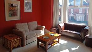 A living room with a red wall, two sofas, a coffee table, and a small side table. - 25 Avenue Victoria, Flat 2 (Scarborough)