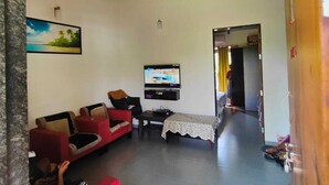 A living room with a flat-screen TV, red sofas, a coffee table, and a ceiling fan.