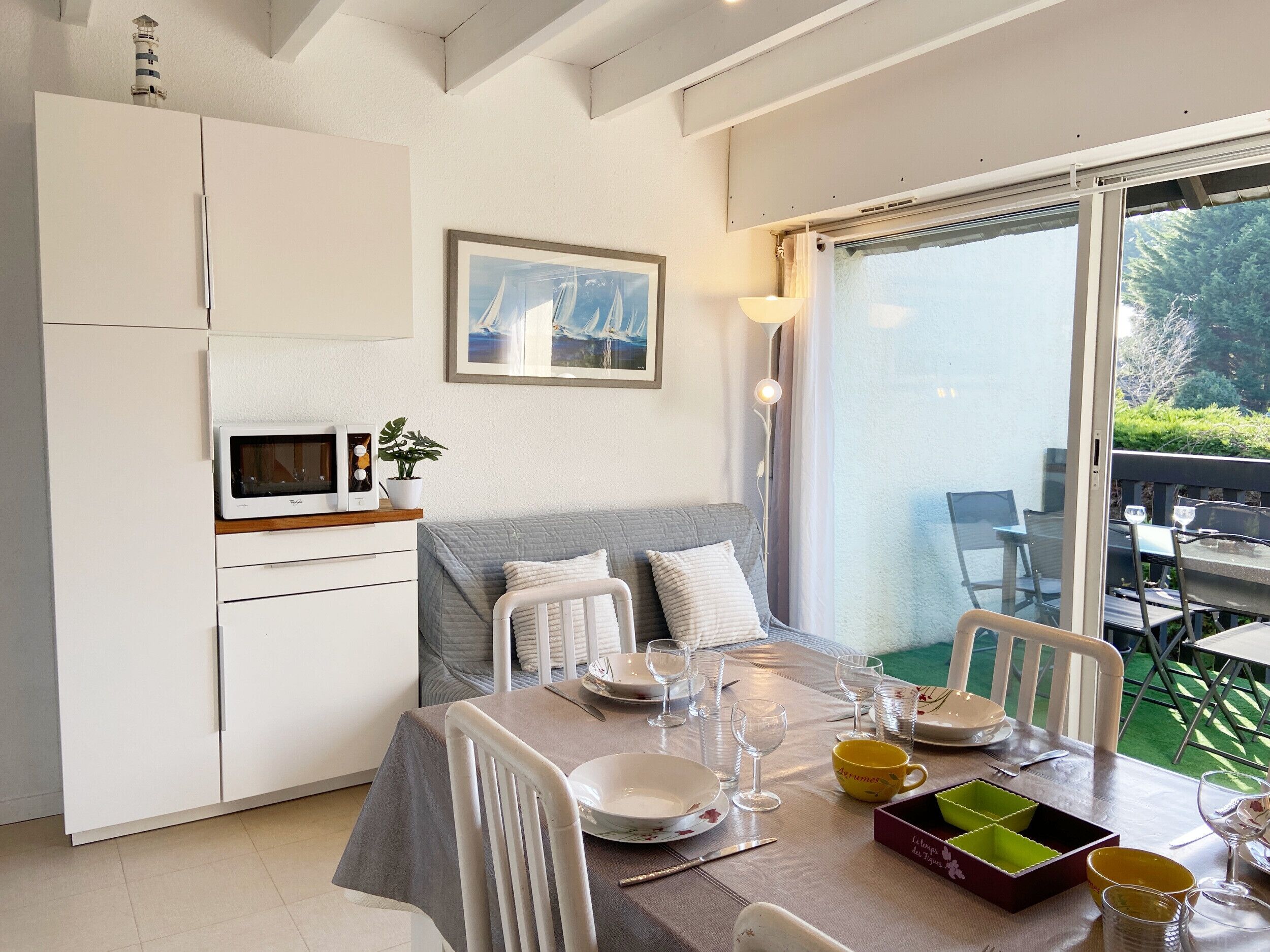 A modern kitchen with white cabinets, a microwave, and a potted plant.
