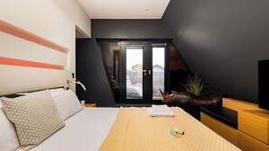 Un dormitorio moderno con cama, televisión y vista al exterior.