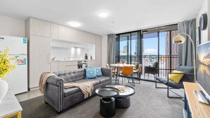 Een modern appartement met een grijze bank, een eettafel en een televisie.