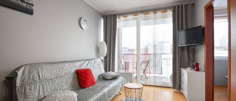 Una sala de estar moderna con un sofá gris, una mesita redonda y un televisor de pantalla plana.
