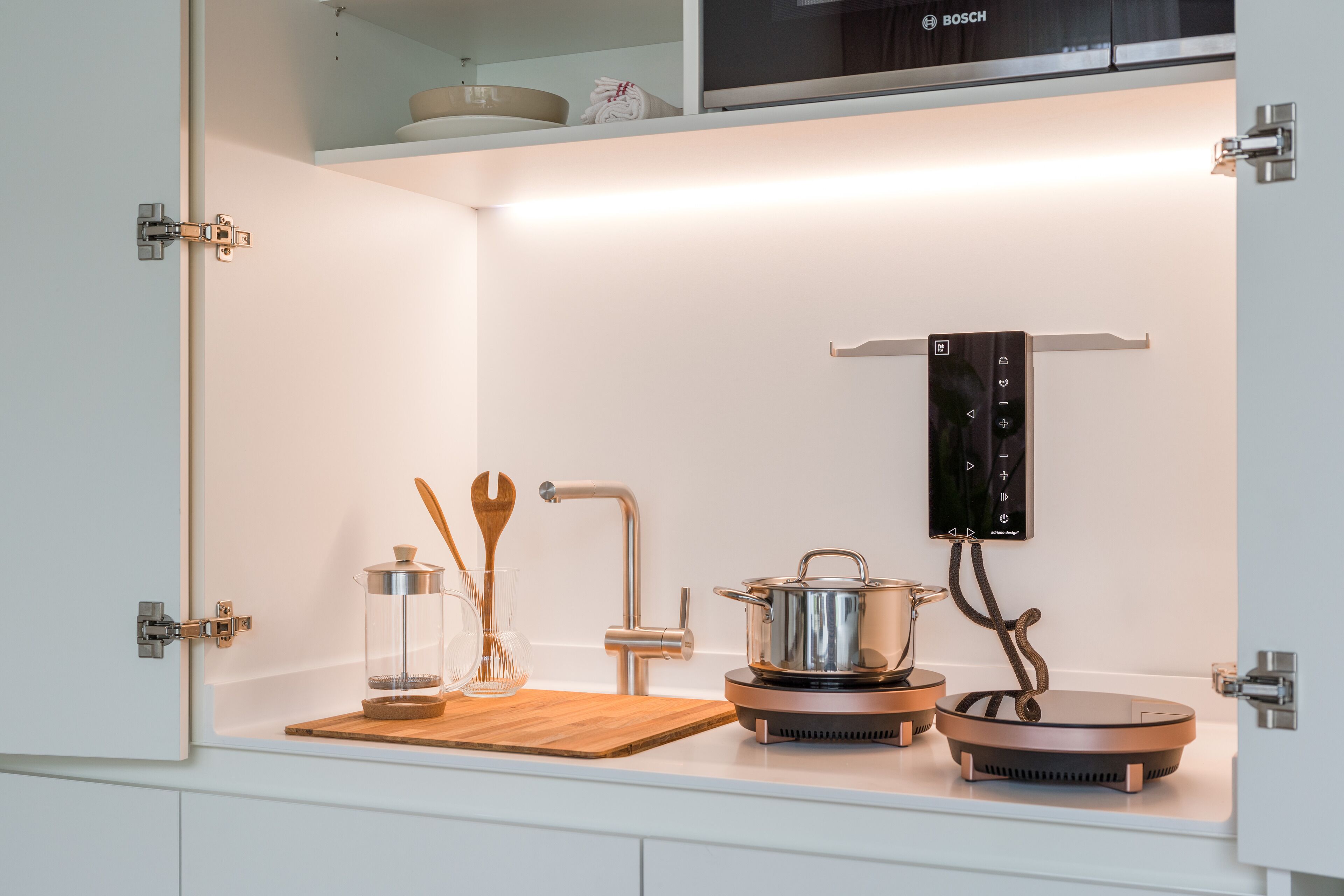 A kitchen with a built-in stove, a hanging towel rack, and various utensils.
