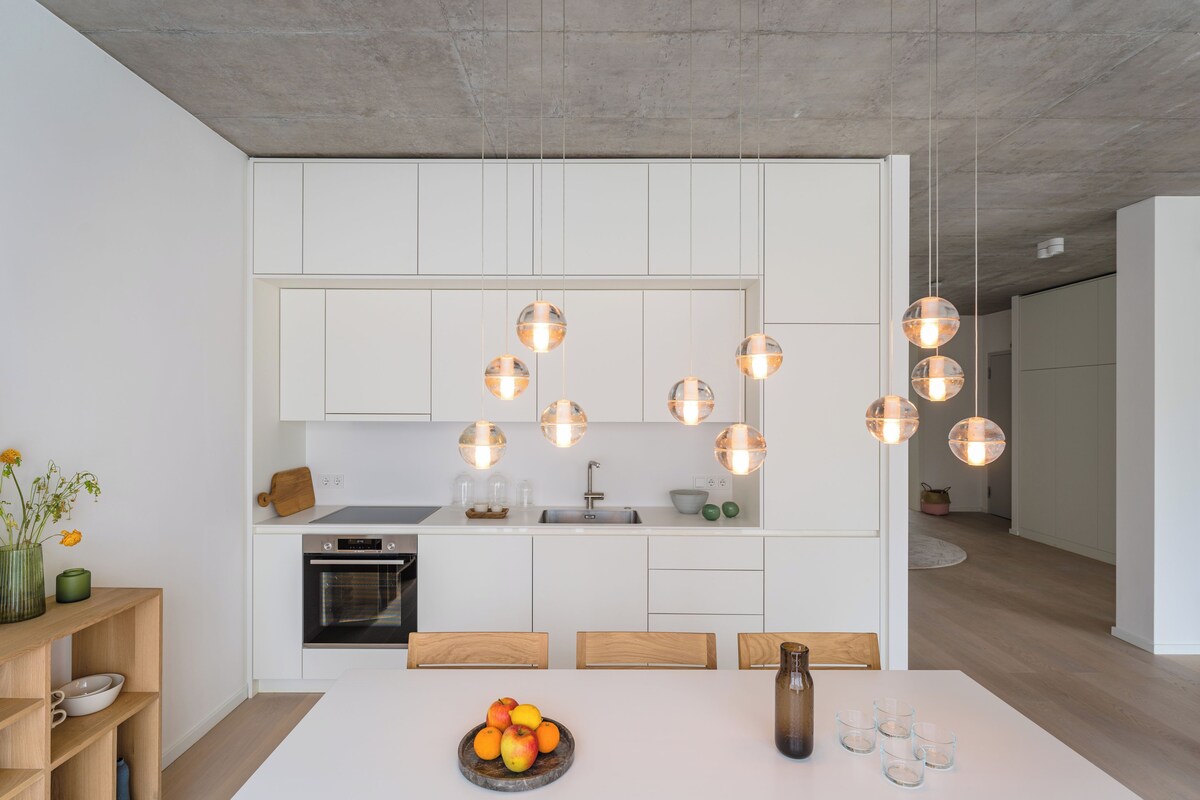 A modern kitchen with white cabinets, a central island, and pendant lighting.