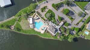 An aerial view of a waterfront property with a swimming pool, parking area, and green spaces. - Lakefront House with Huge Swim Spa (Montgomery)