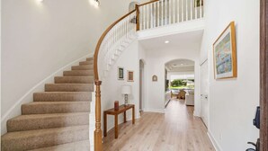 A staircase leading to a second floor with a white railing, a wooden table with a lamp, and framed pictures on the walls. - Lakefront House with Huge Swim Spa (Montgomery)
