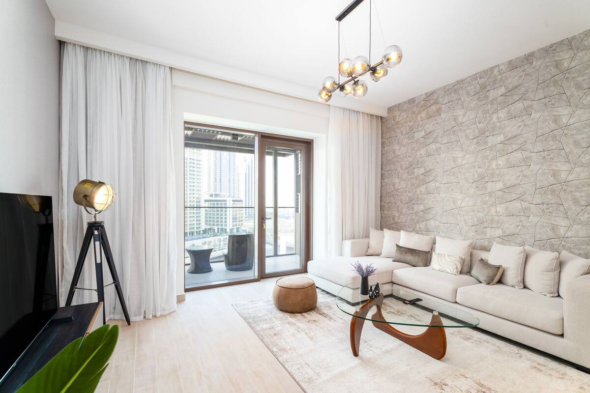 A modern living room with a sofa, a glass coffee table, a floor lamp, and a stone accent wall.