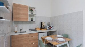 Eine kleine Küche mit einem Holzkasten, einer Mikrowelle, einem Spülbecken und einem Esstisch mit Stühlen.