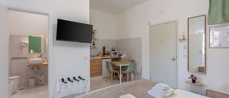 Een moderne hotelkamer met een bed, een bureau, een stoel, een televisie, een badkamer en een groen gordijn.
