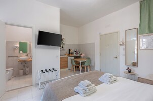 Una habitación de hotel moderna con cama, escritorio, silla, televisión, baño y cortina verde.