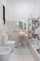 Un baño moderno con inodoro, bidé, lavamanos y ducha.