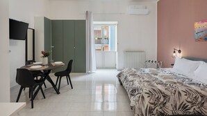 Ein modernes Schlafzimmer mit einem Bett, einem Schreibtisch mit Stühlen, einem Esstisch und einem Fernseher.
