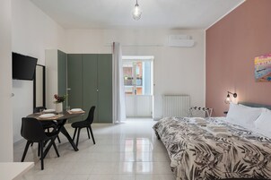 Un dormitorio moderno con cama, escritorio con sillas, mesa de comedor y televisor.