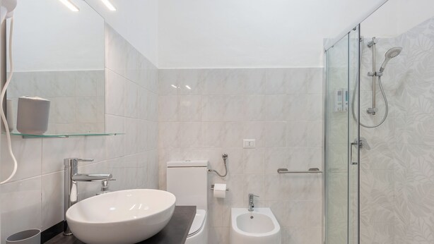 Ein modernes Badezimmer mit einem großen, ovalen Waschbecken, einem Bidet und einer Duschkabine.